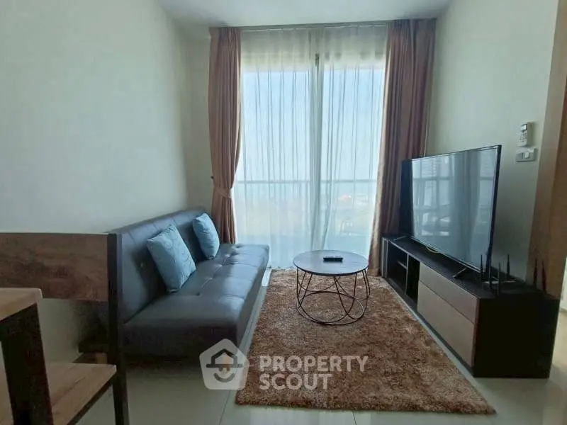 Modern living room with large window, stylish sofa, and flat-screen TV.