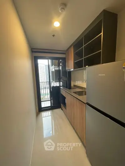 Modern kitchen with sleek cabinetry and stainless steel fridge in a compact layout.