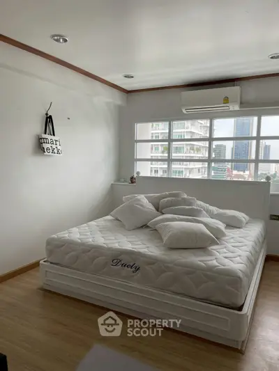 Bright bedroom with large windows and modern decor in urban apartment.