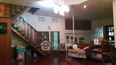 Spacious living room with elegant staircase and chandelier, perfect for family gatherings.