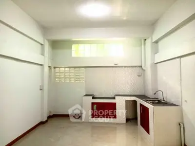 Minimalist kitchen with white walls and red cabinets, featuring a sleek countertop and sink.
