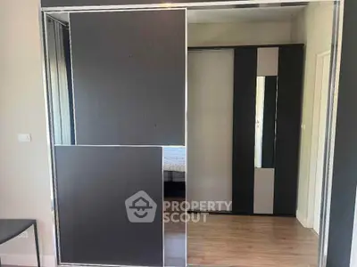 Modern bedroom with sleek sliding wardrobe doors and wooden flooring.