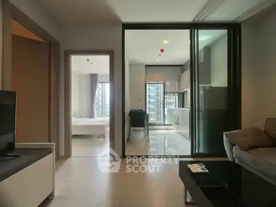 Modern apartment interior with open layout connecting living room, kitchen, and bedroom, featuring sleek design.