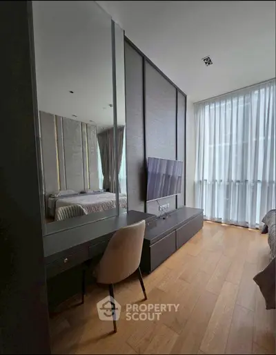 Modern bedroom with sleek design, featuring a wall-mounted TV and elegant furnishings.