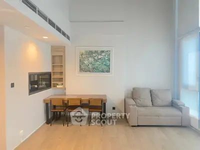 Modern living room with cozy sofa and dining table, featuring minimalist decor and natural light.