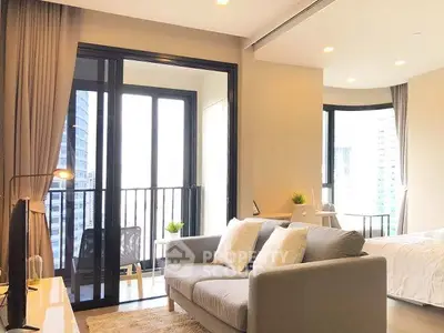 Modern open-plan living room with balcony and city view, featuring cozy sofa and natural light.