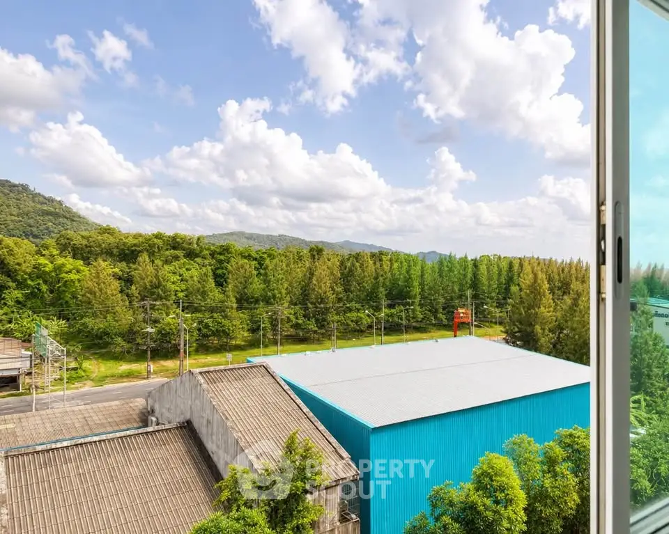 Stunning panoramic view from high-rise window overlooking lush greenery and distant mountains.