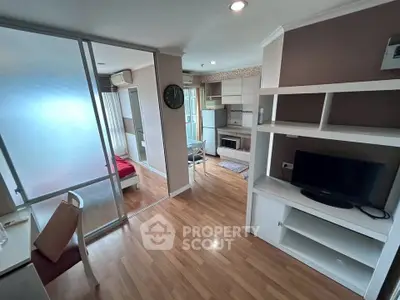 Modern open-plan living room with kitchen and bedroom, featuring wooden flooring and sleek furniture.