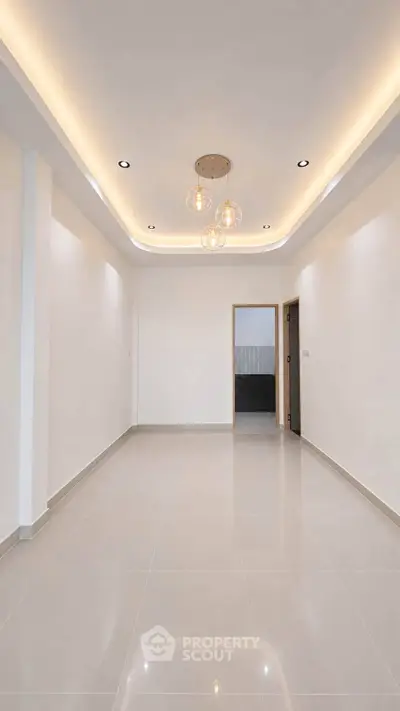 Spacious modern living room with elegant ceiling lights and glossy tiled flooring.