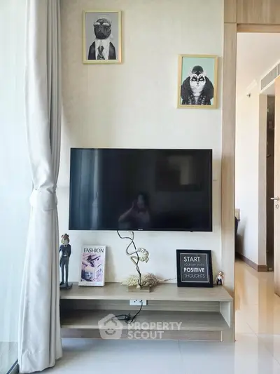 Modern living room with stylish decor and wall-mounted TV, featuring elegant artwork and natural light.