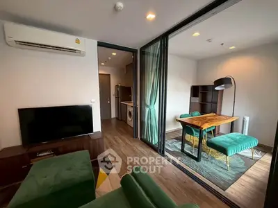 Modern living room with green velvet furniture and open kitchen layout in stylish apartment.