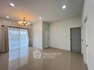 Spacious empty living room with elegant chandelier and large windows
