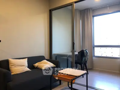 Modern living room with cozy sofa and natural light from large window.