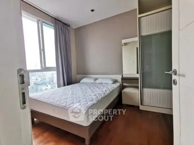 Modern bedroom with large window and wooden flooring in high-rise apartment