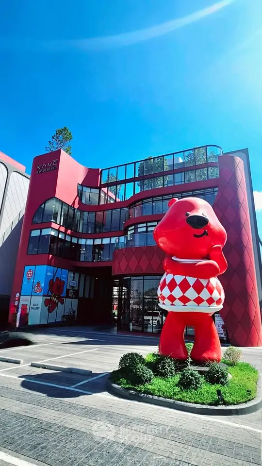 Modern commercial building with unique red facade and large bear sculpture, perfect for businesses seeking high visibility.