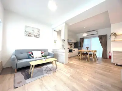 Spacious open-plan living room with modern kitchen and dining area, featuring stylish decor and ample natural light.