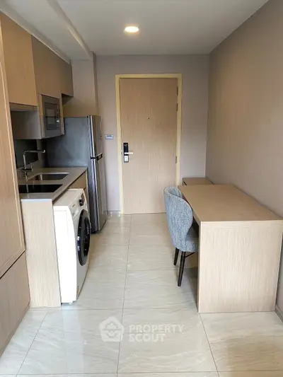 Modern compact kitchen with washing machine and dining area in a stylish apartment.