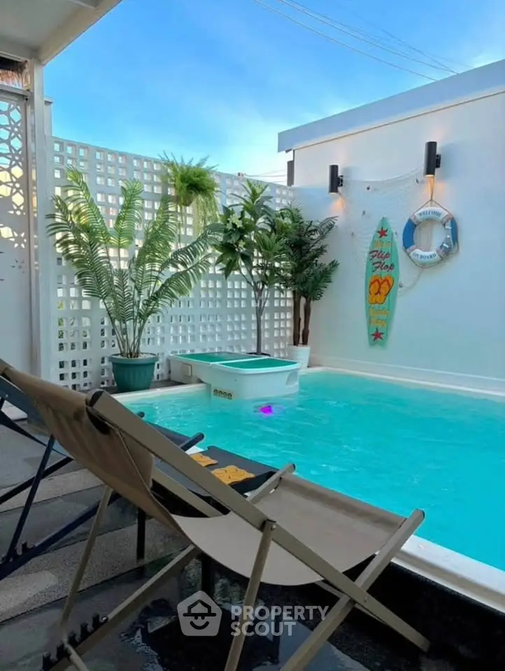 Chic outdoor pool area with tropical decor and lounge chairs, perfect for relaxation.