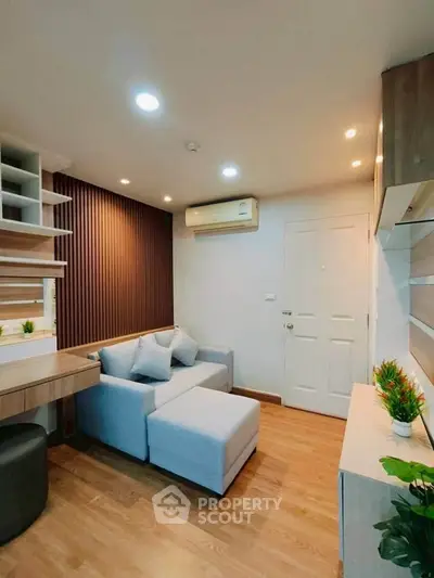 Modern living room with stylish furniture and wooden flooring, featuring a cozy sofa and elegant shelving.