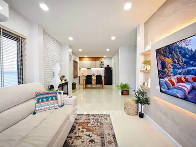 Modern open-plan living room with stylish decor and large wall-mounted TV