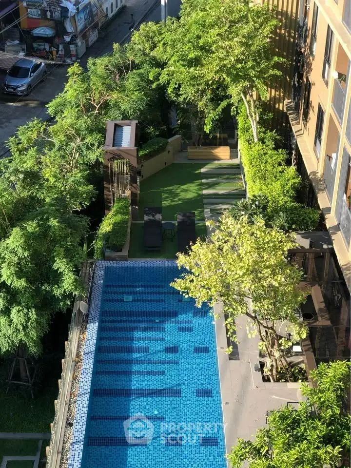 Luxurious rooftop pool with lush greenery and seating area, perfect for relaxation and leisure.