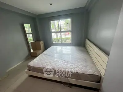 Spacious bedroom with large window and modern furniture in a serene setting.