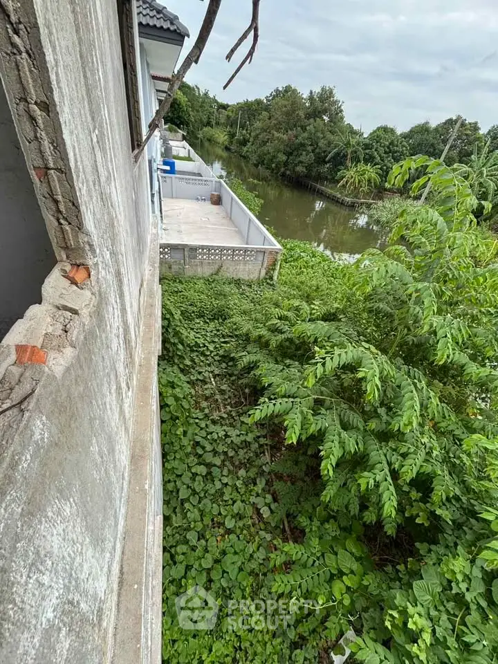 Riverside property with lush greenery and spacious balcony offering serene views.