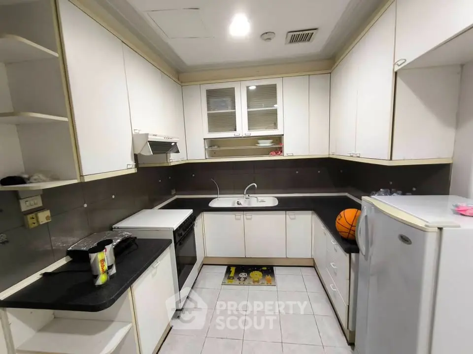 Modern kitchen with sleek white cabinets and black countertops, featuring a compact layout and essential appliances.
