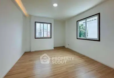 Spacious empty room with wooden flooring and large windows, ideal for customization.
