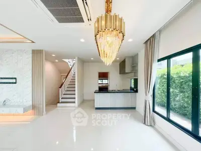 Luxurious open-plan living room with elegant chandelier and modern kitchen in a bright, spacious home.