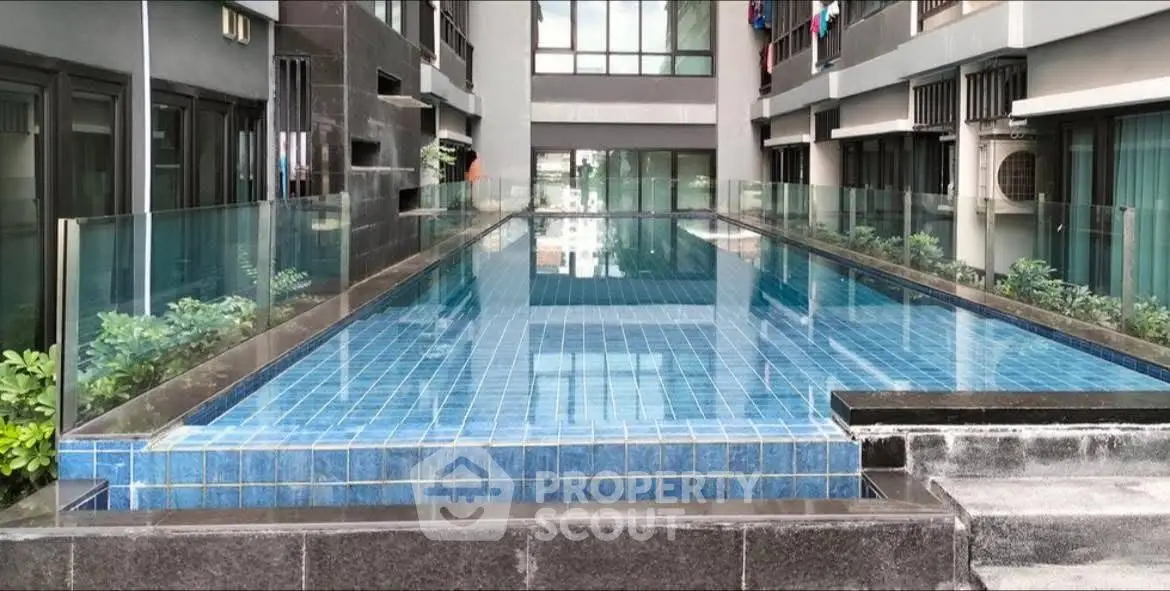Luxurious modern apartment complex with sleek glass-enclosed swimming pool and contemporary architecture.