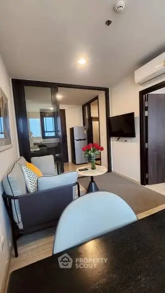 Modern living room with stylish decor and open layout, featuring a cozy seating area and wall-mounted TV.