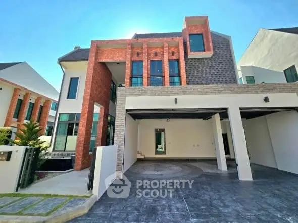 Modern two-story house with unique brick and stone facade, spacious driveway, and contemporary design.