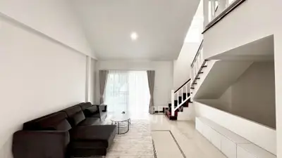 Spacious modern living room with sleek black sofa and elegant staircase