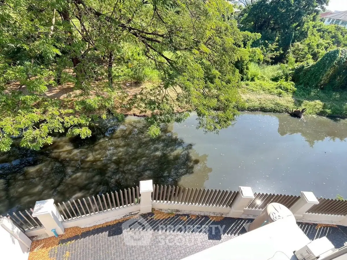Scenic view of lush greenery and tranquil waterway from a residential balcony.