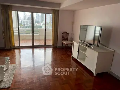Spacious living room with parquet flooring and balcony view in urban apartment