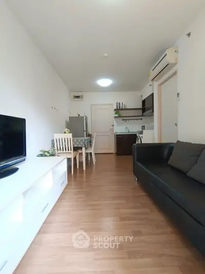 Modern living room with open kitchen, wooden flooring, and sleek furniture