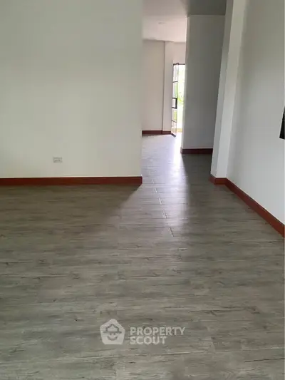 Spacious empty room with wooden flooring and natural light, ideal for customization.