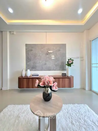 Modern living room with elegant decor and soft lighting, featuring a stylish wooden console and plush rug.