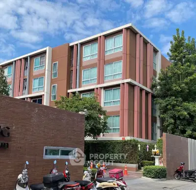 Modern apartment building with lush greenery and parked scooters