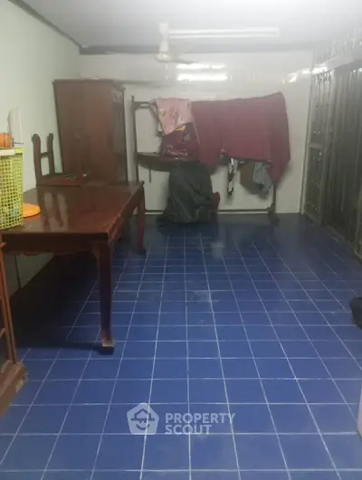 Spacious room with blue tiled floor and wooden furniture, ideal for versatile use.