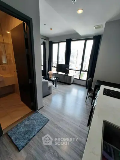 Modern living room with city view, featuring sleek furniture and large windows for natural light.