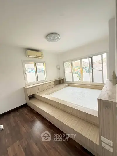 Modern bedroom with platform bed and large windows in a bright, airy space.