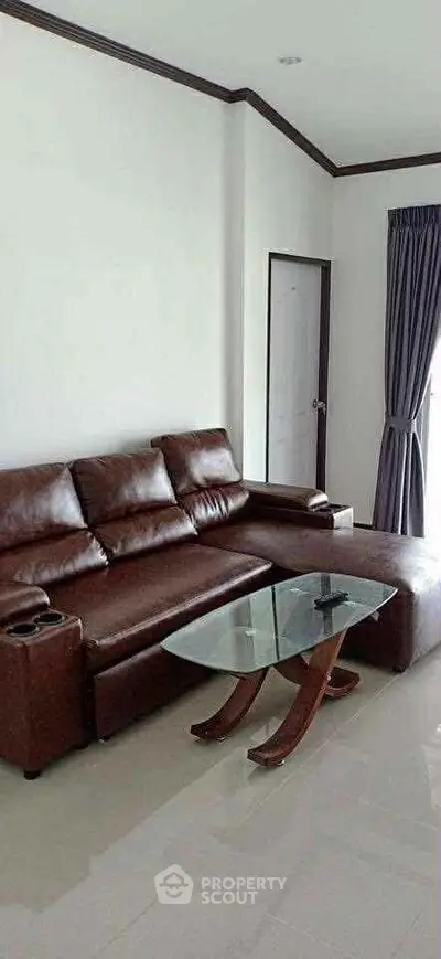 Modern living room with brown leather sofa and glass coffee table