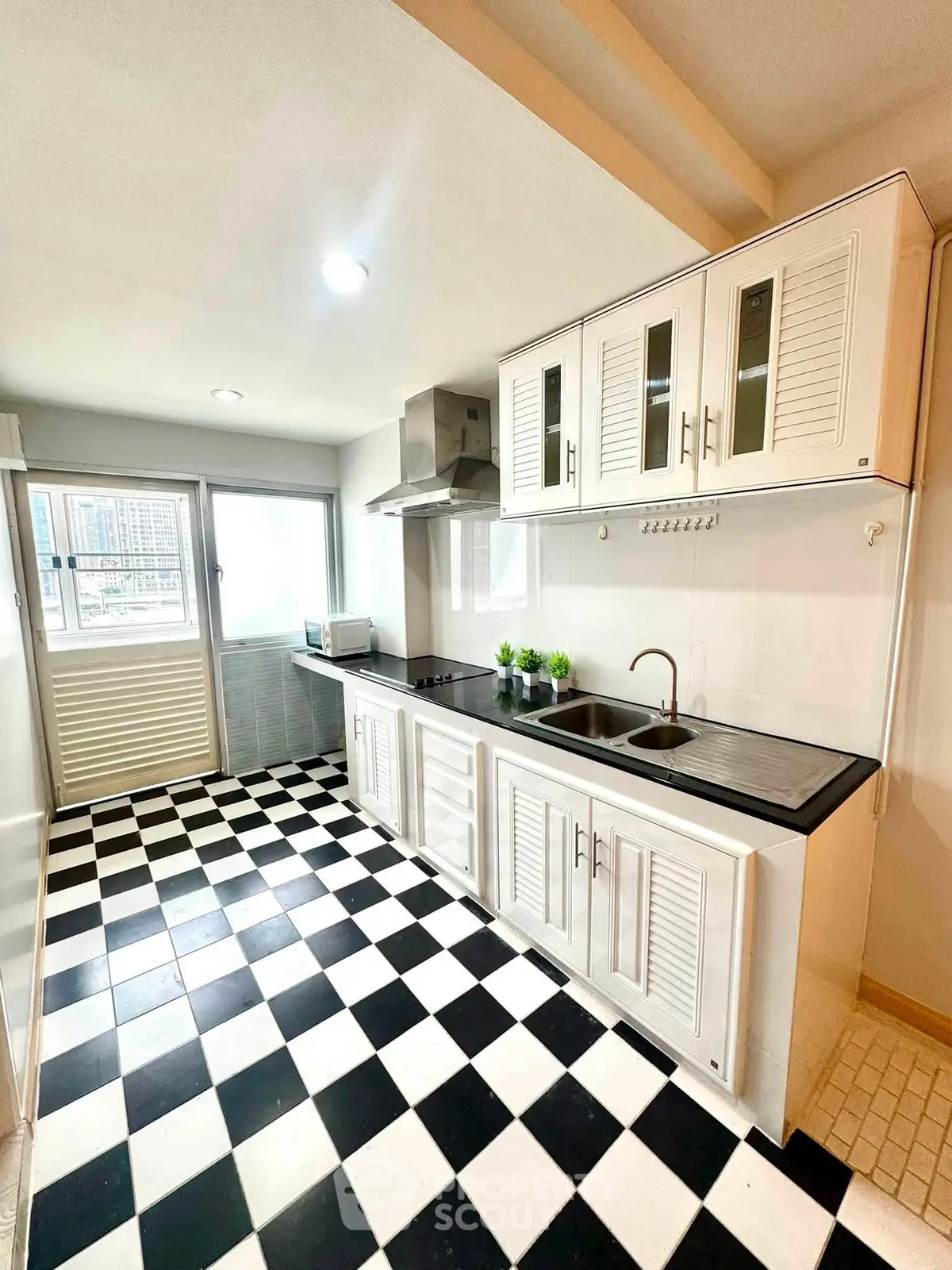 Spacious kitchen with modern cabinetry and checkered flooring, featuring ample natural light and sleek appliances.