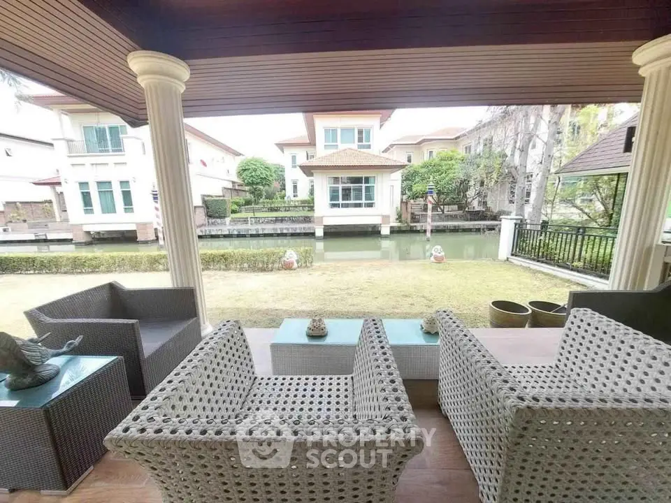 Charming patio with wicker furniture overlooking serene canal and elegant homes.