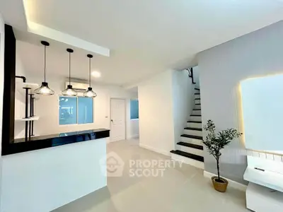 Modern open-plan living space with stylish lighting and staircase