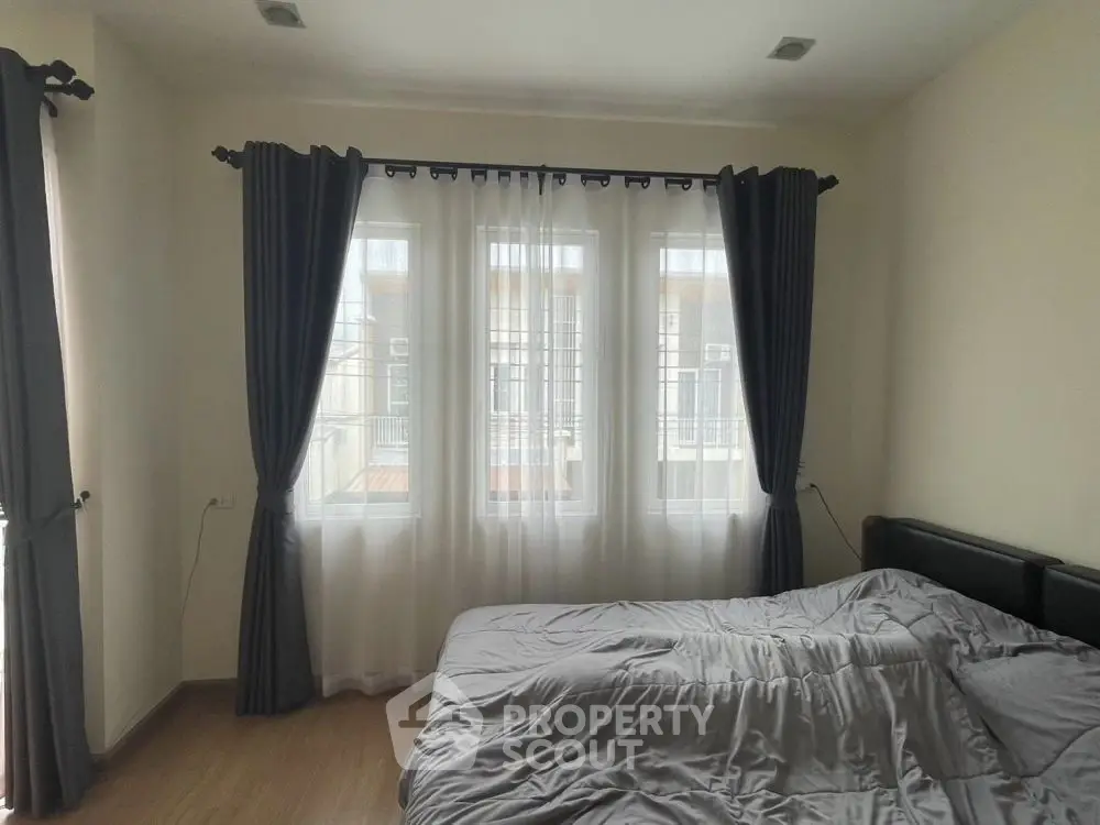 Cozy bedroom with large windows and elegant curtains, perfect for natural light lovers.