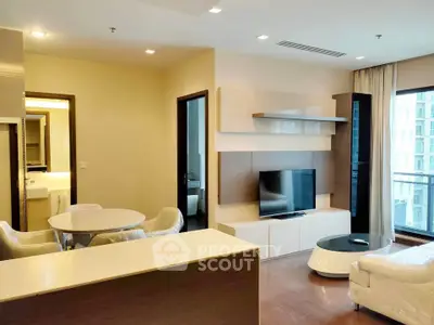 Modern living room with sleek furniture and large TV, featuring a balcony with city view.