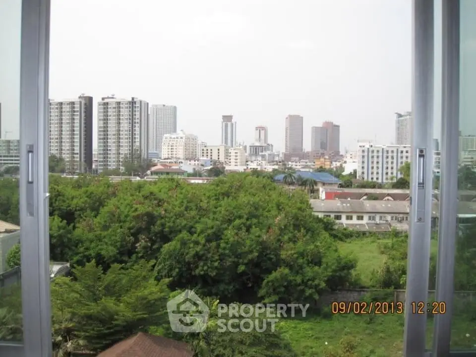 Stunning cityscape view from a high-rise window, showcasing lush greenery and modern skyline.